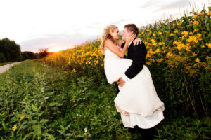 A bride and groom kissing in a field of sunflowers.