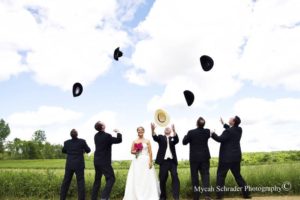 Bride and other men throwing hats in the air