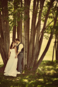 A bride and groom are posing under a tree.