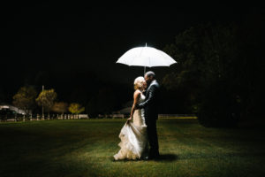 Bride and groom kissing holding an umbrella