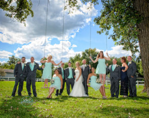 A group of bridesmaids and groomsmen posing on swings.