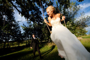 A bride and groom swinging on a swing.