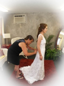 A woman putting on a wedding dress in a room.