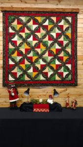 A christmas quilt hanging on a wall.