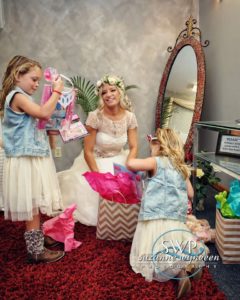 Bride and bridesmaids playing with gifts in front of a mirror.