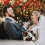 Bride and groom laughing holding flowers