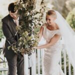 Bride and groom holding a plant laughing