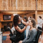 A woman getting her makeup done in a barn.