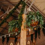 A wedding with greenery hanging from the ceiling.