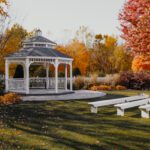 A white gazebo with benches in the fall.