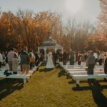 A wedding ceremony in the fall with a gazebo in the background.