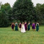 A group of bridesmaids in green dresses standing in a field.