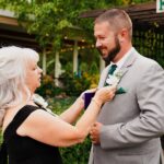 A woman putting on a man's boutonniere.