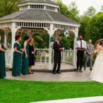 A wedding ceremony in front of a gazebo.