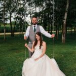 Bride sitting on the swing and groom behind