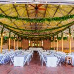 A wedding reception set up in a greenhouse with greenery hanging from the ceiling.