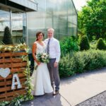 A bride and groom standing in front of a wooden pallet sign.