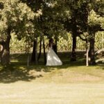 A bride in a wedding dress standing under a tree.