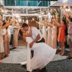 A bride and groom kissing in front of sparklers.