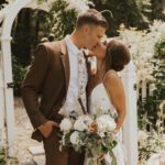 Bride and groom kissing, holding flowers