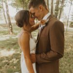 A bride and groom hugging in the woods.