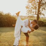 A bride and groom kissing in a field at sunset.