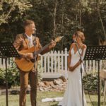 A bride and groom singing in front of a microphone.