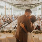 A bride and groom kissing at their wedding reception.