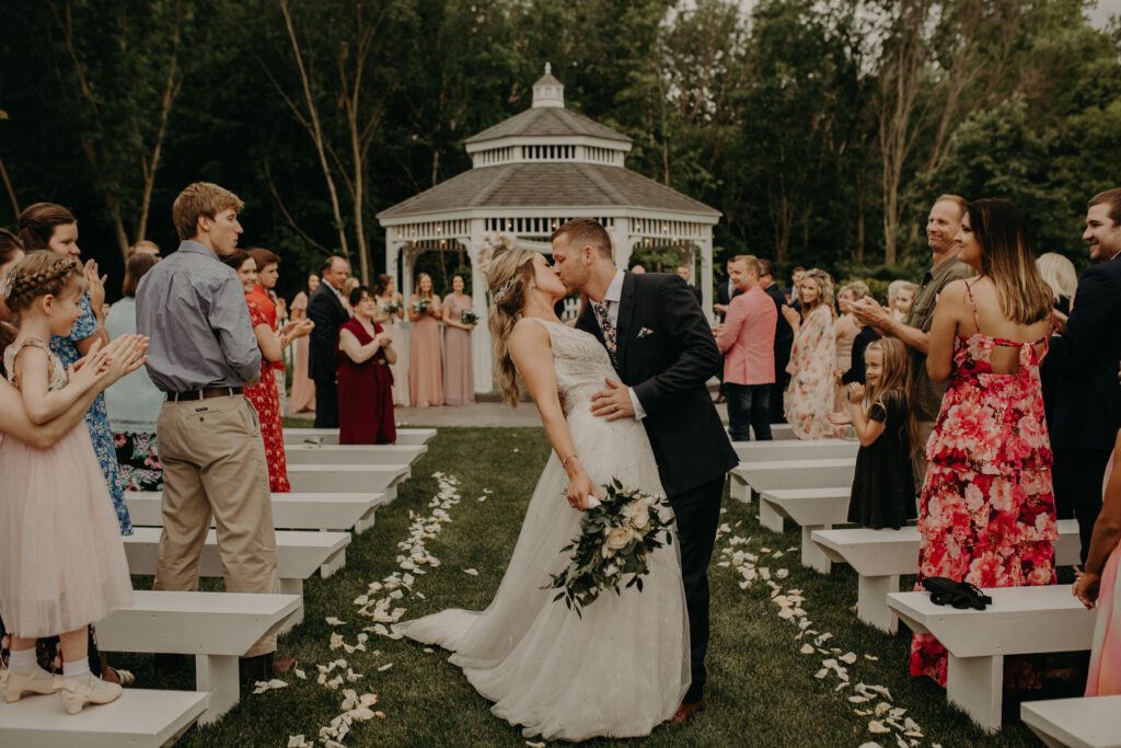 A bride and groom kiss in front of a gazebo.