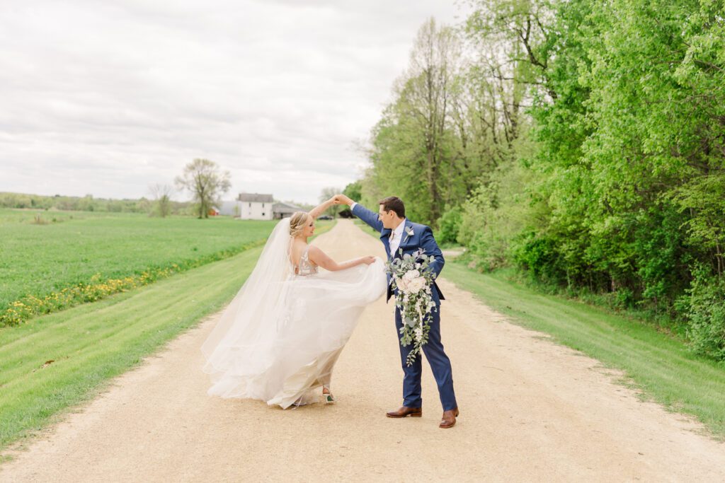 A bride and groom dancing on a dirt road.