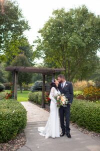 A bride and groom kissing in front of a gazebo.