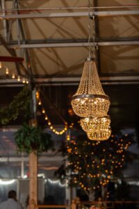 A chandelier hangs over a table in a barn.